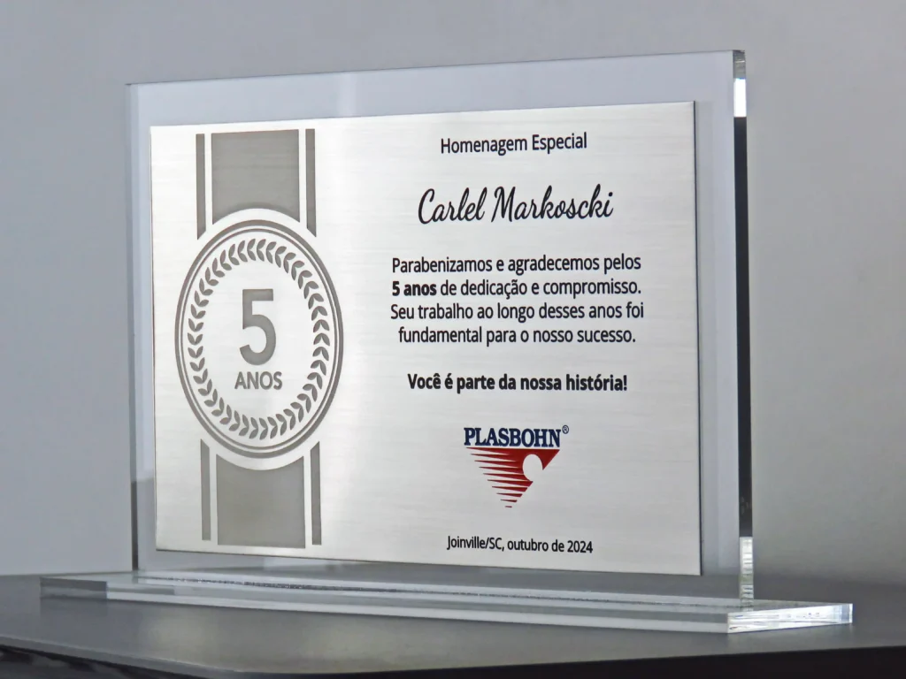 Placa de homenagem em aço inox, gravada em baixo relevo, com estrutura em acrílico cristal.