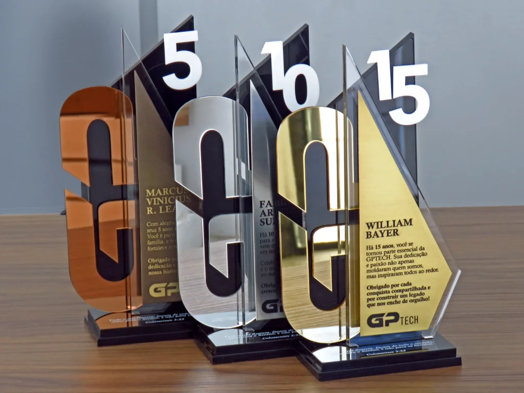 Troféus personalizados, 5, 10 e 15 anos, envolvendo metais e acrílicos.