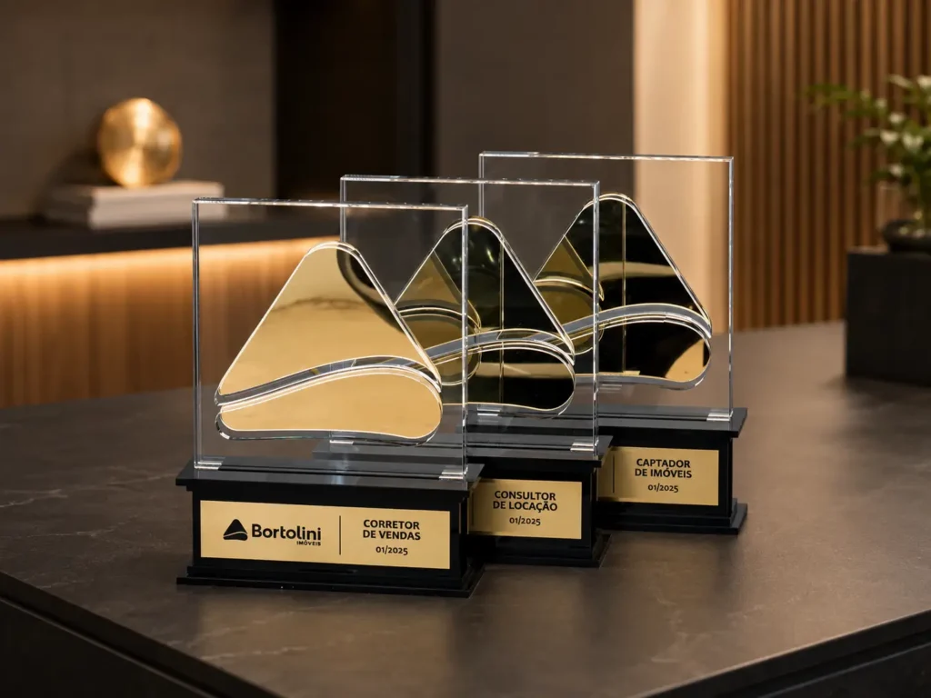 Três troféus para corretores em cima de uma mesa.